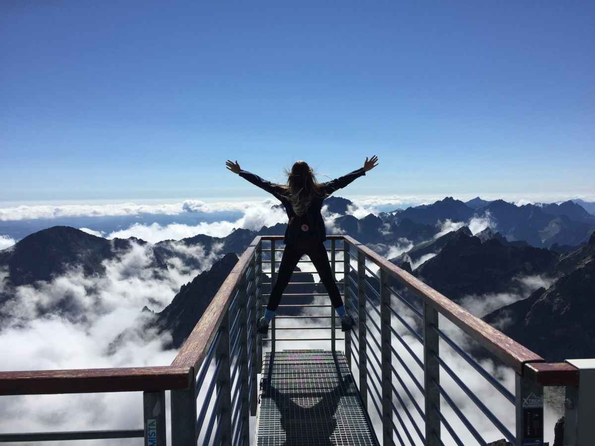 person standing on an observatory with arms wide open in joy